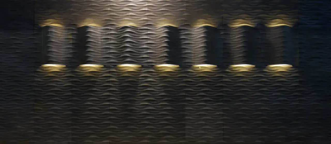 Detalles de cómo panelar una pared con un diseño ondulado, iluminado con luces cálidas que resaltan las texturas.