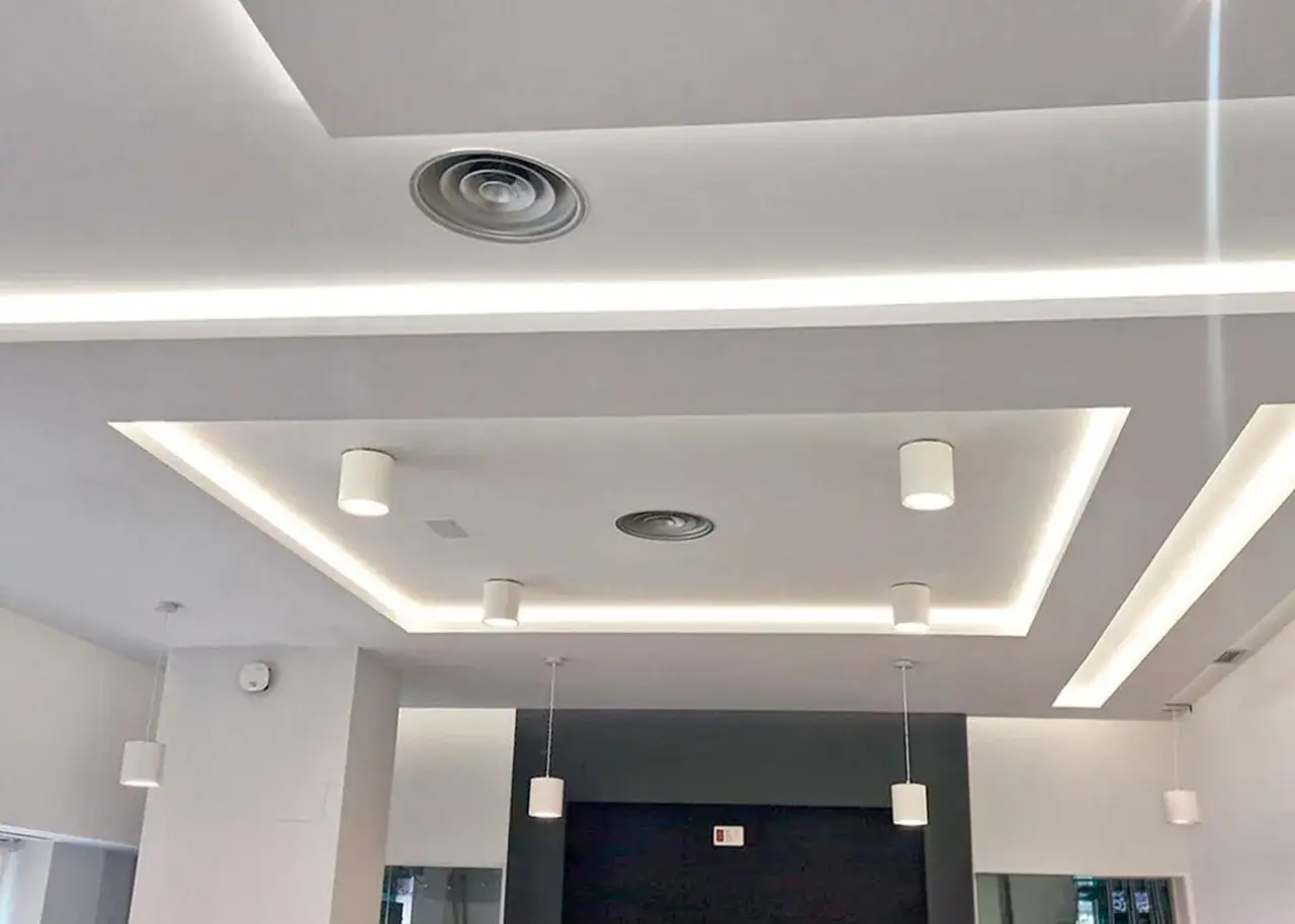 Techo pladur moderno con iluminación indirecta y focos cilíndricos. Un diseño elegante y funcional.
