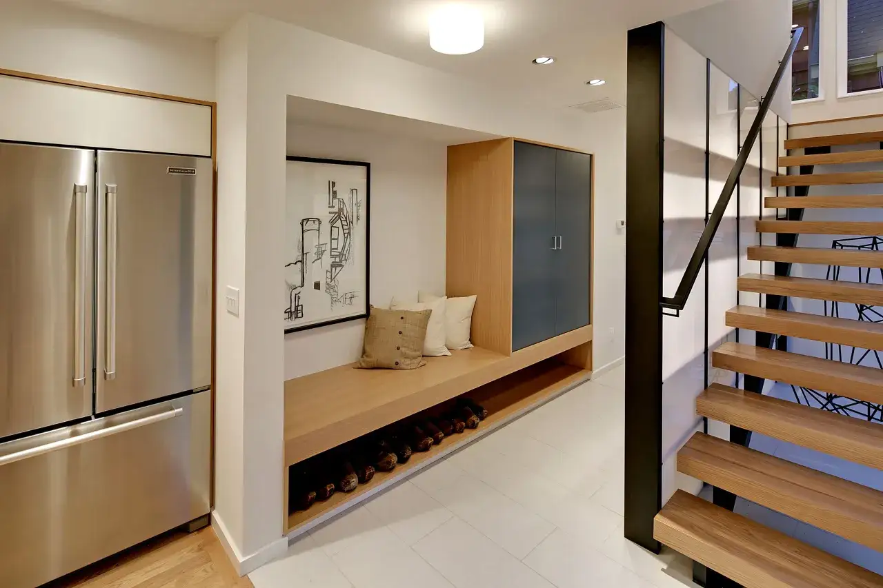 Ideas para pasillos estrechos como decorar un pasillo: refrigerador, banco de madera con cojines, armario y escaleras flotantes.