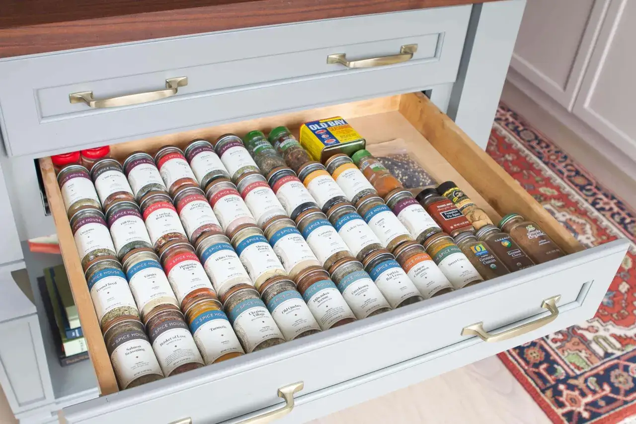 Cajón abierto con frascos de especias perfectamente organizados para organizar cocina.