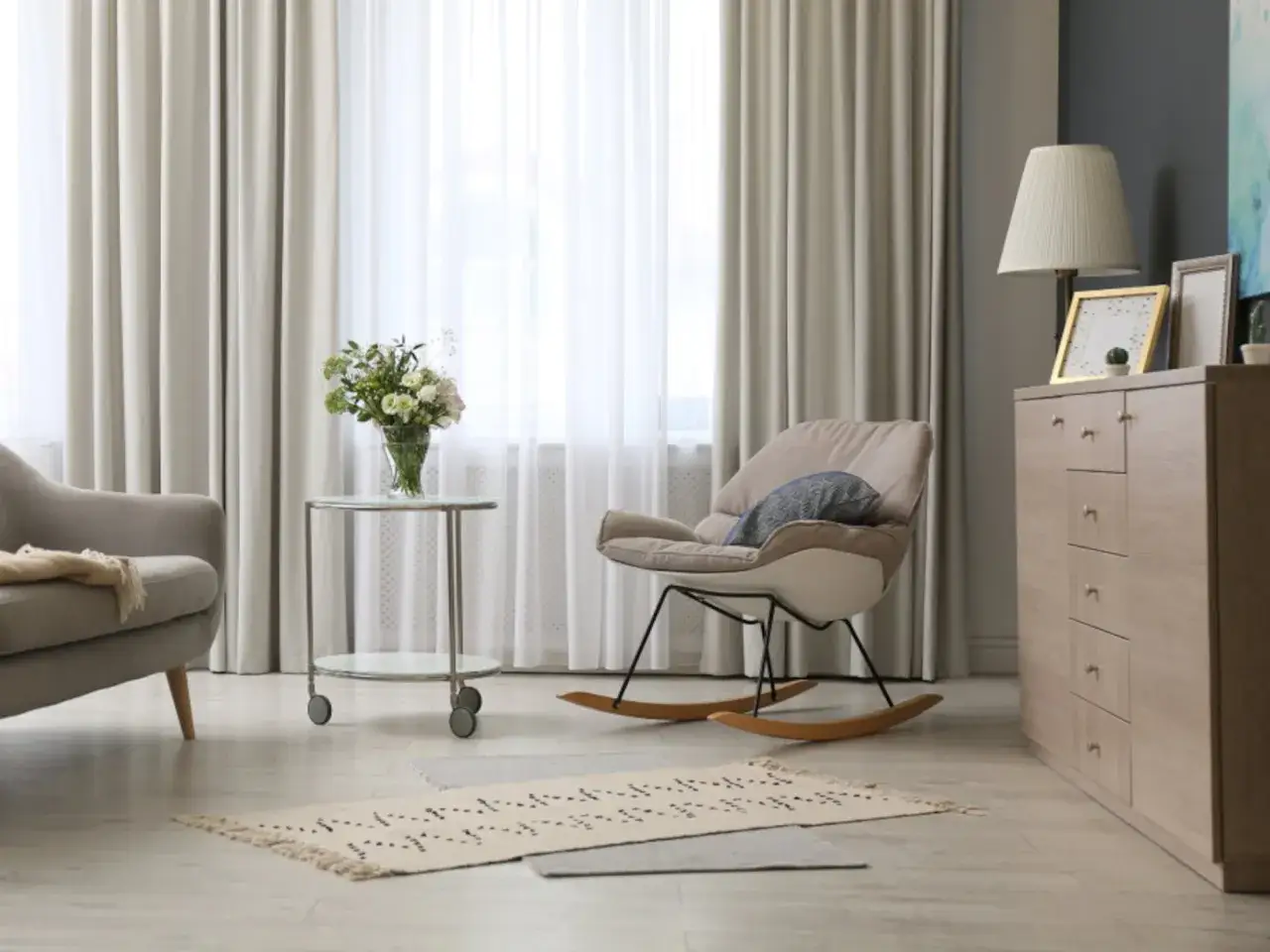 Elegantes cortinas de salón, un sillón mecedora y un jarrón con flores. Las últimas tendencias en cortinas para tu salón.