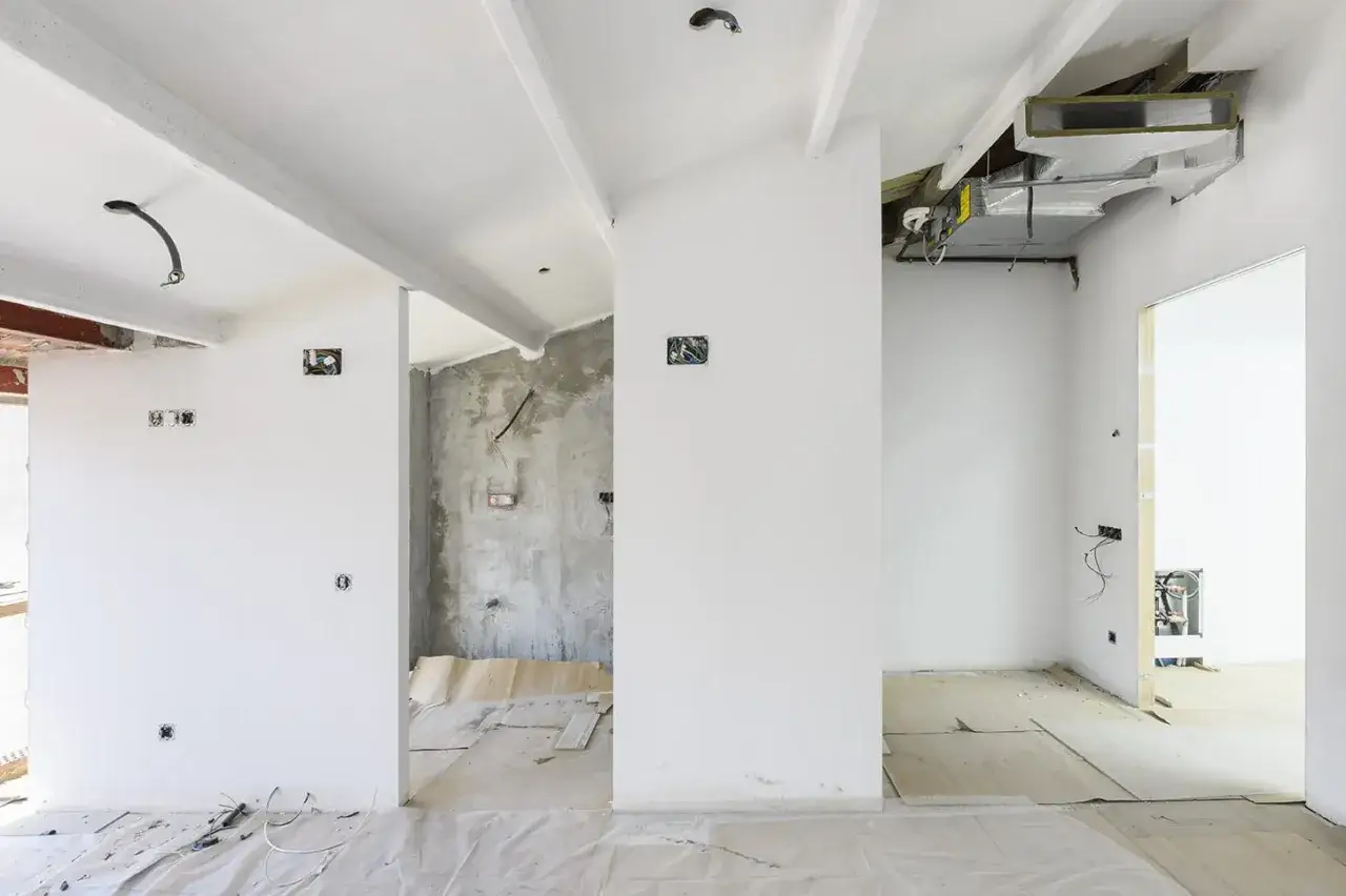 Instalaci&oacute;n de falso techo con conductos de aire acondicionado visibles. Cables y cajas el&eacute;ctricas expuestas en paredes en construcci&oacute;n.