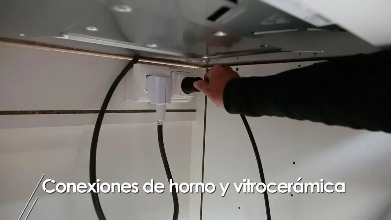 Mano conectando el enchufe para horno y vitrocerámica a la toma de corriente.