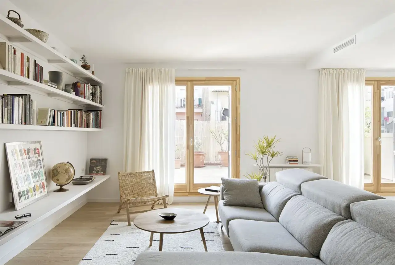 Un salón moderno con estanterías llenas de libros, un sofá gris y una silla de mimbre. Un espacio acogedor, ideal para sencillas salas pequeñas.