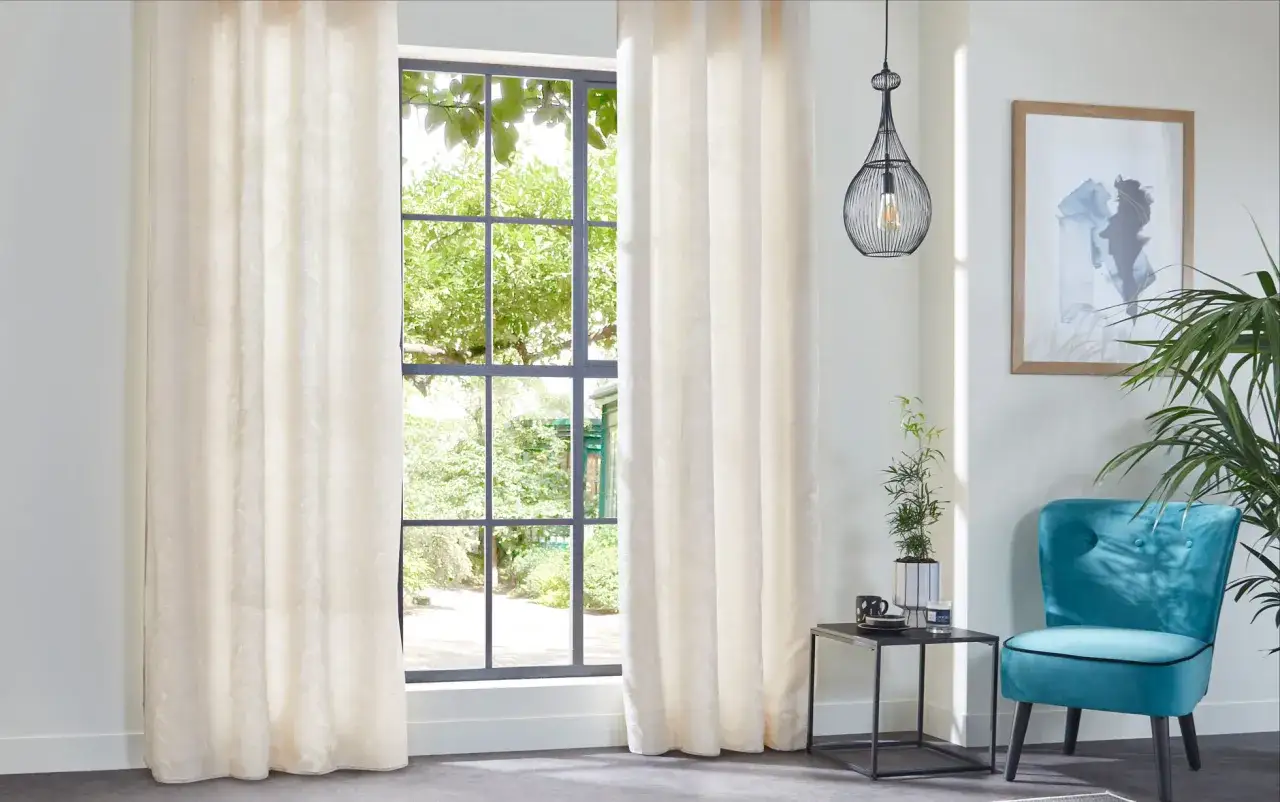 Cortinas de tela crema con sutil estampado floral, un ejemplo de tipos de cortinas para ventanas que aportan elegancia y luz.