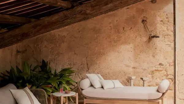 Un rincón acogedor para aprovechar buhardilla muy baja. Sofá, plantas y detalles rústicos bajo vigas de madera.